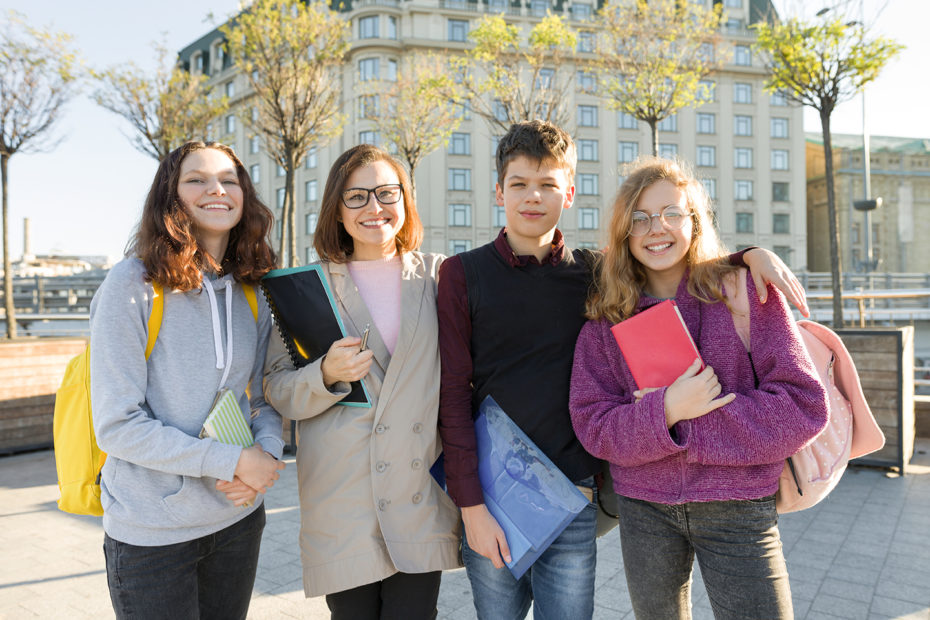 Group of students with teacher, teenagers talking to a female teacher