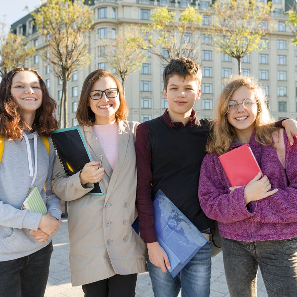 Group of students with teacher, teenagers talking to a female teacher